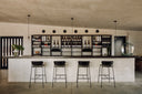 Modern bar interior with shelves stocked with bottles and stools in a minimalistic setting.
